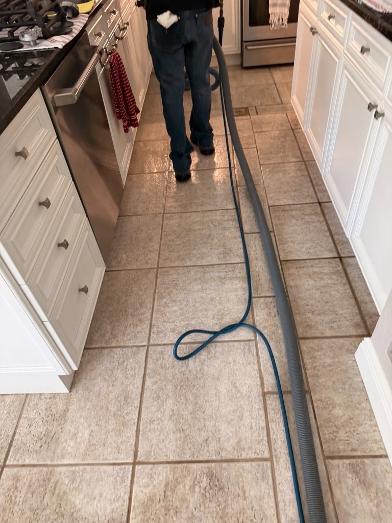 HydroLux technician cleaning kitchen tile and grout with extraction hose in Wesley Chapel home