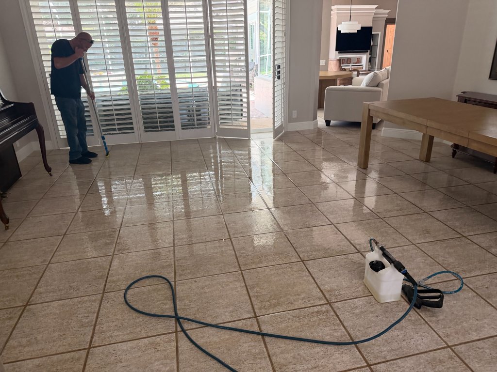 HydroLux technician applying grout sealer to large format tile floor in residential living room Florida