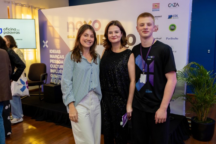 Três participantes posando no palco do NEXO 2026