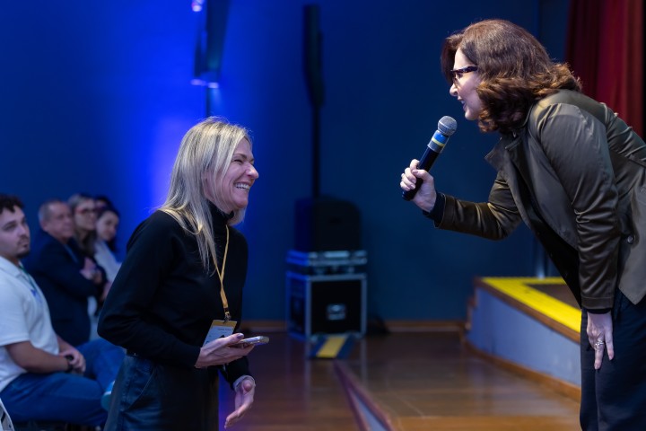 Palestrante conversando com participante no palco do NEXO 2026