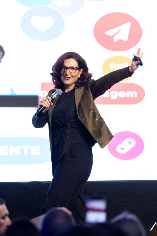 Palestrante com blazer oliva e tela de ícones sociais