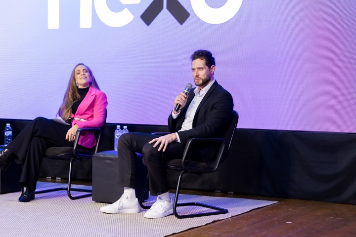 Painel com dois palestrantes no palco do NEXO 2026