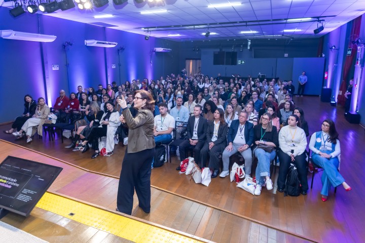 Palestrante no palco com auditório ao fundo