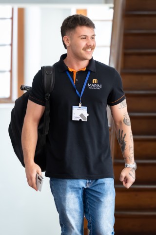 Participante caminhando com crachá do NEXO 2026