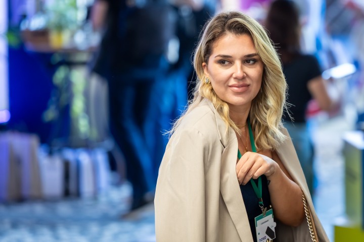 Participante loira com blazer bege no NEXO 2026