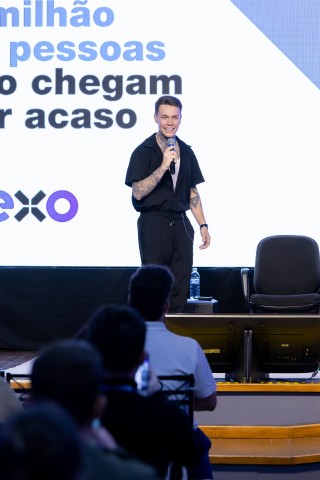 Palestrante jovem com tatuagens no palco do NEXO
