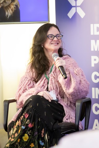 Palestrante sentada no palco com cardigan rosé