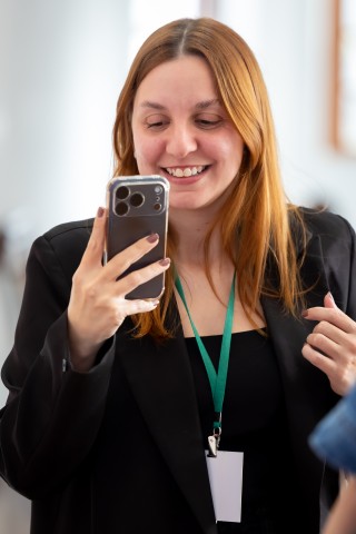 Participante olhando o celular no NEXO 2026