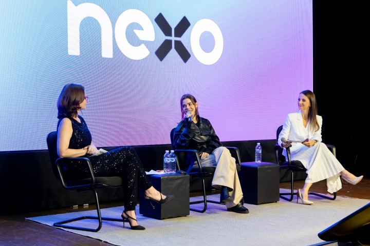 Painel com três mulheres sentadas no palco do NEXO