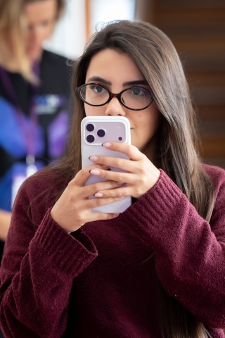 Participante fotografando com o celular no NEXO 2026