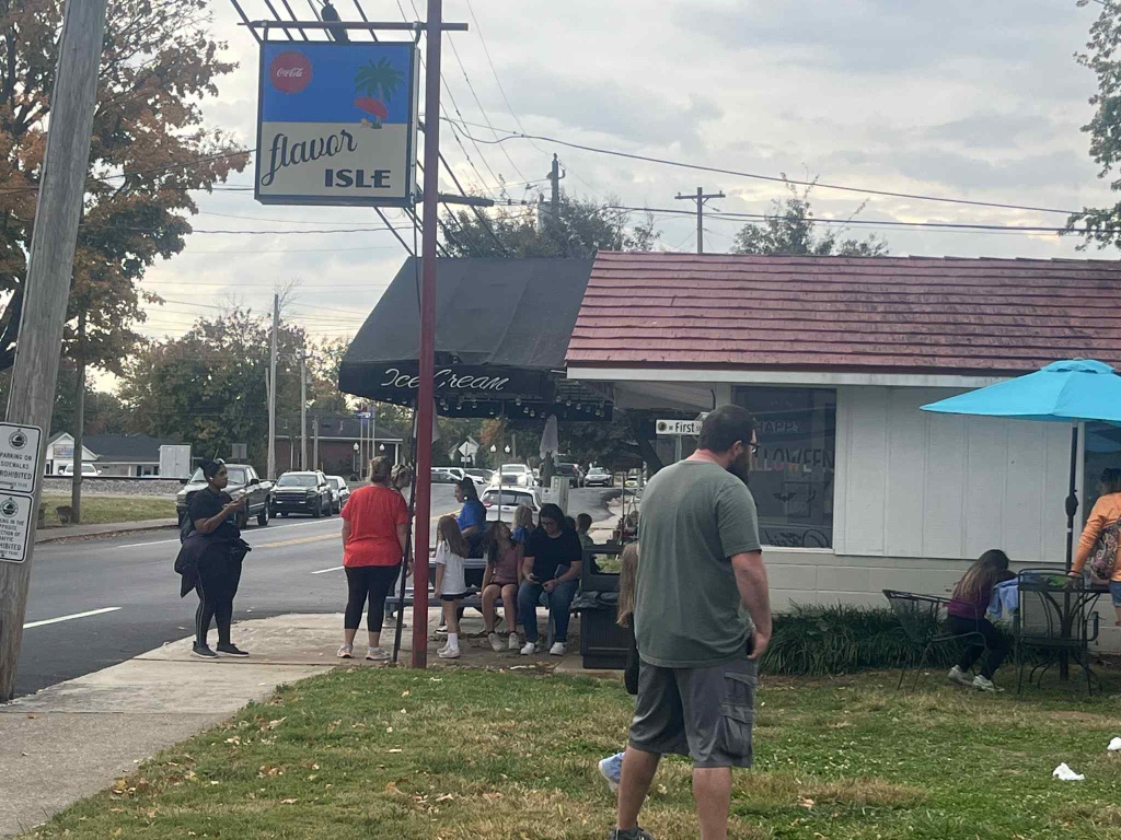 Community walk group holding milkshakes under the sign