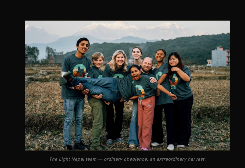 The Light Nepal team gathered in a Nepal field with mountains rising behind them
