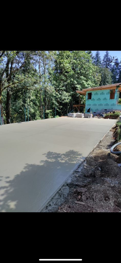 Smooth light grey concrete patio slab curing in wooded setting