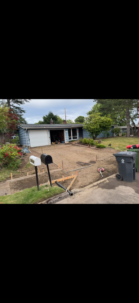 Gravel driveway base framed with wooden formwork and a drainage pipe before the pour