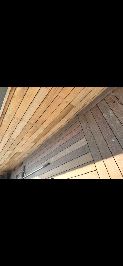Close-up of deck plank installation showing board spacing and joinery against a wooden overhead structure