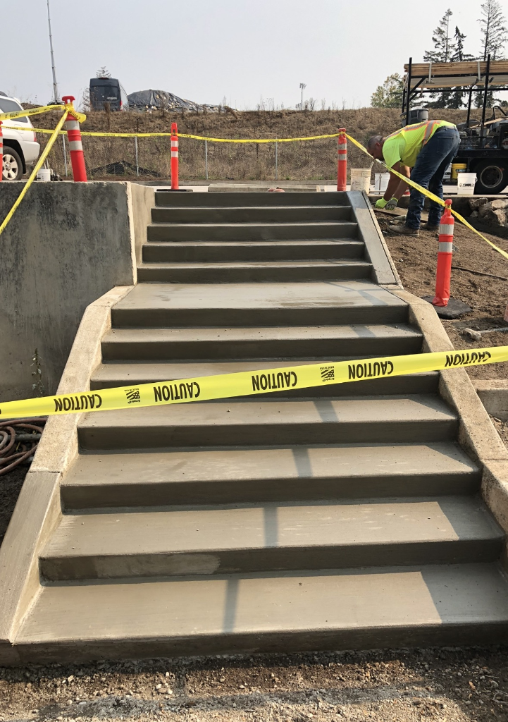 Freshly poured concrete entry steps with smooth grey finish flanked by side walls
