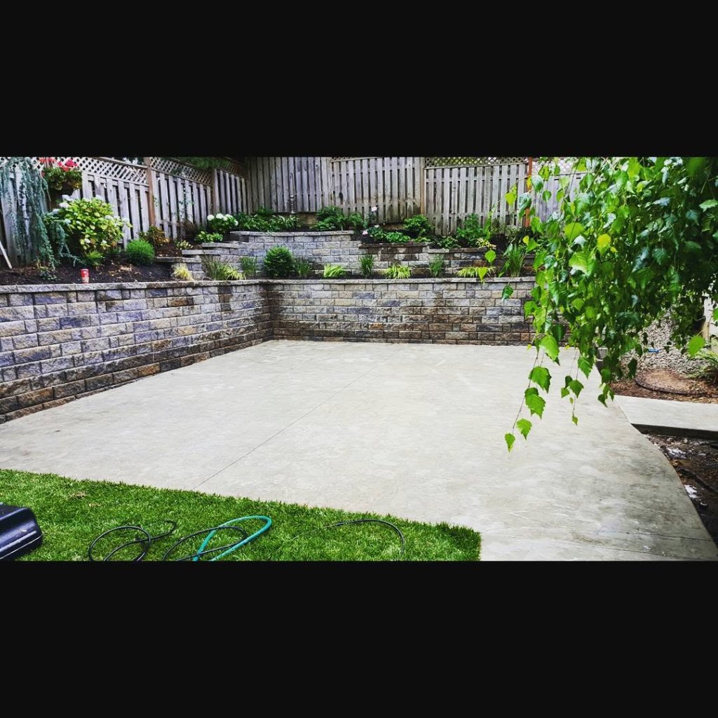 Slate concrete patio with multi-tiered retaining wall and landscaping