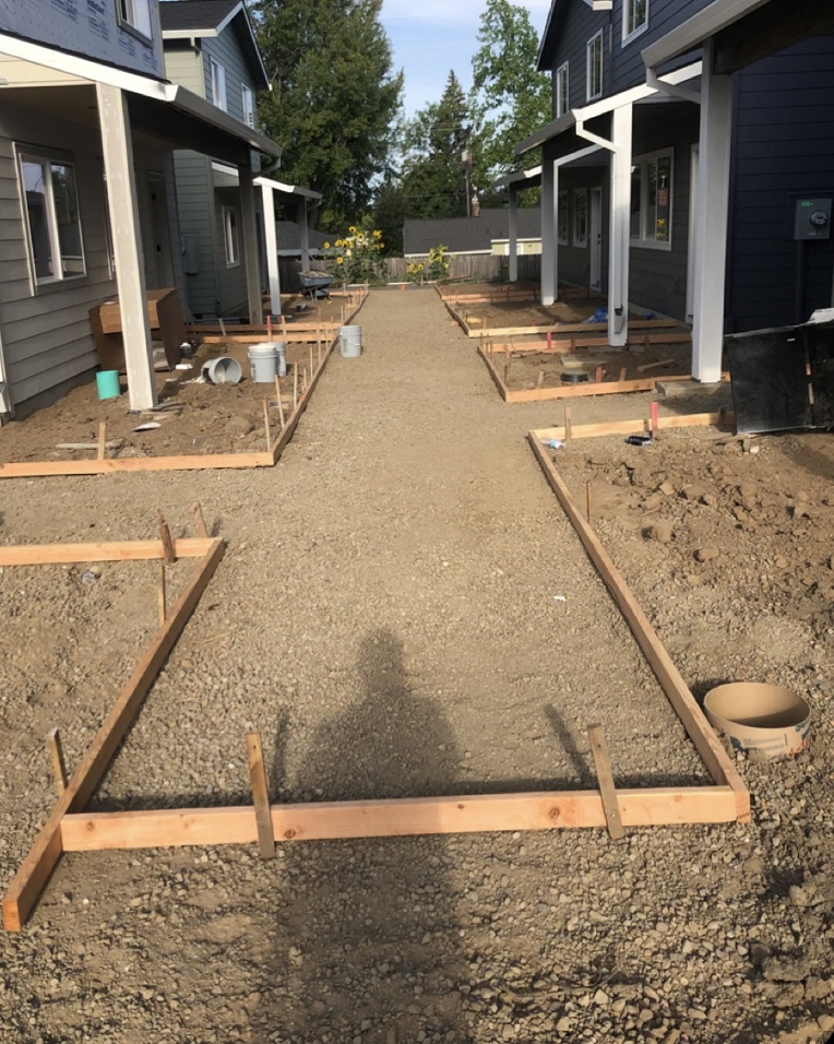 Site prepared for a concrete steps pour with wooden formwork framing the staircase between two houses