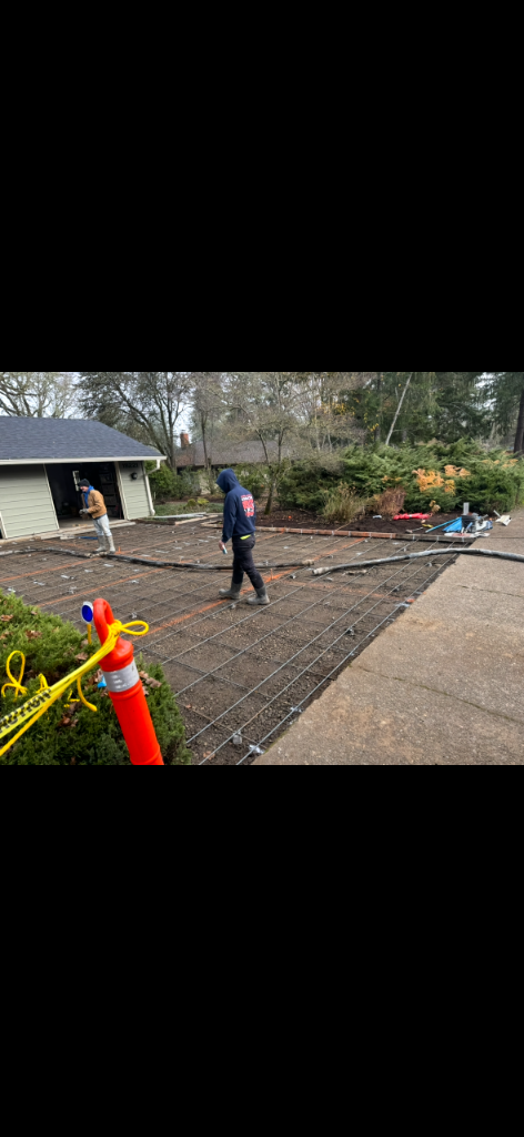 Driveway prepared for a concrete pour with wire mesh, string lines, and workers on site