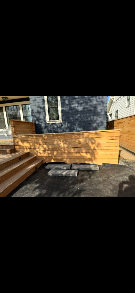 Completed horizontal-slat wood fence beside a tiered deck edge