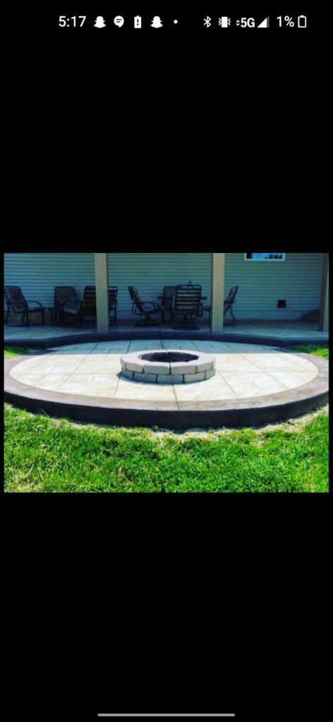 Circular stamped concrete patio with a block fire pit and a dark curved border