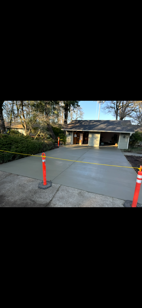 Freshly poured smooth light-grey concrete driveway in front of a garage