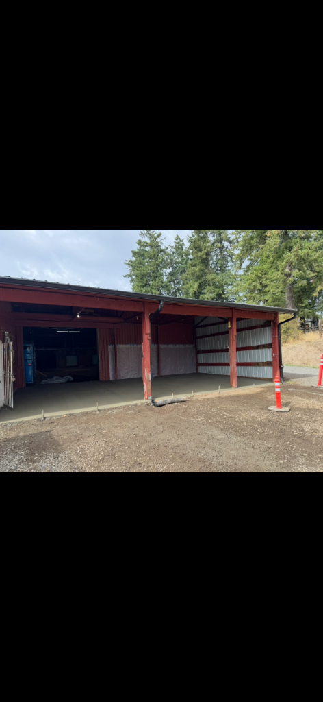 Freshly poured smooth concrete floor inside a red pole barn structure