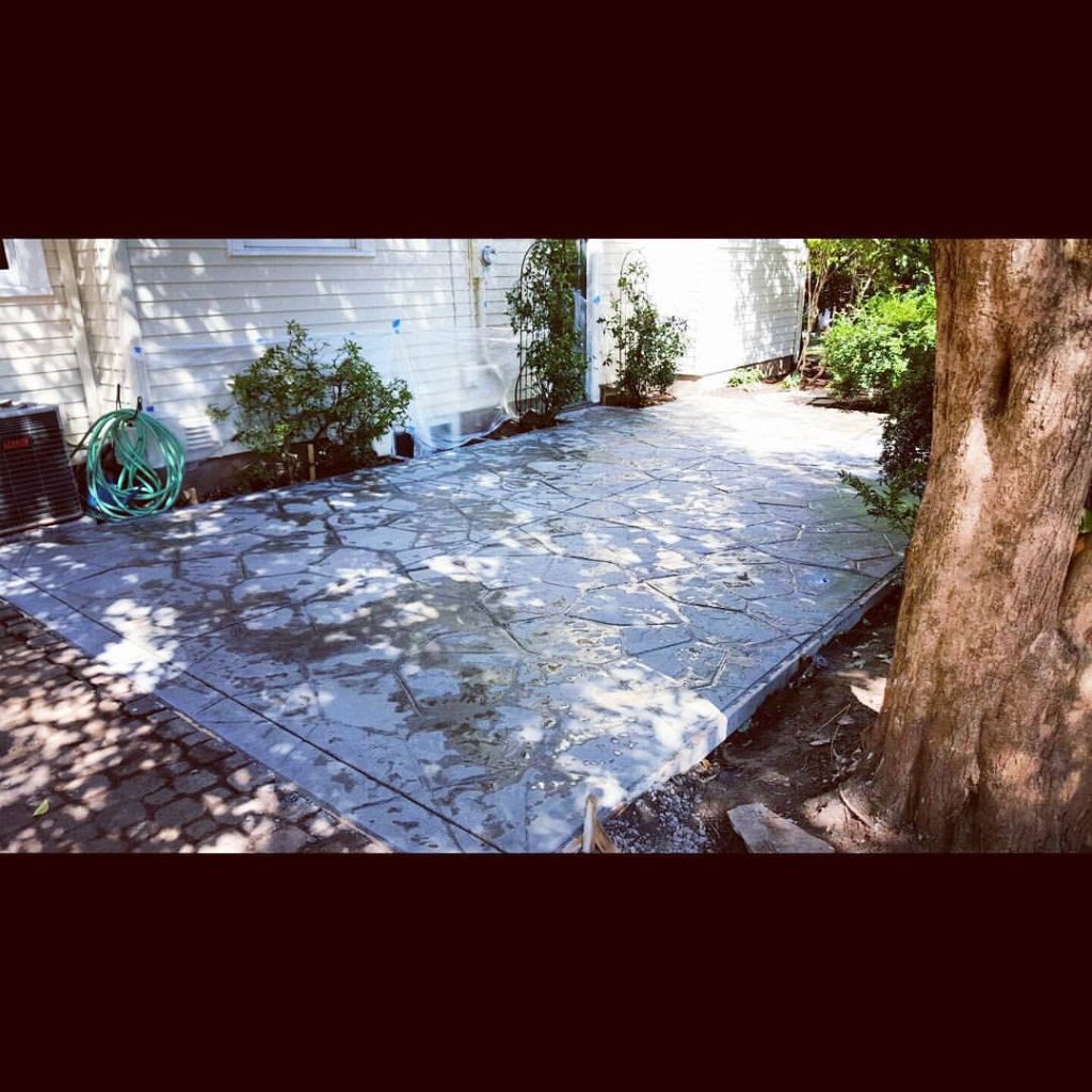 Flagstone stamped concrete patio with smooth border beside white house