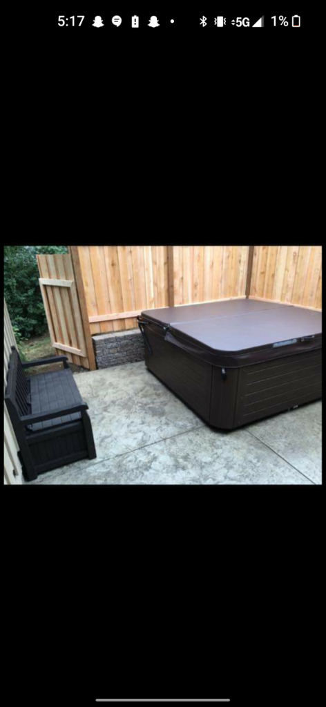 Completed stamped concrete patio with hot tub and stone retaining wall