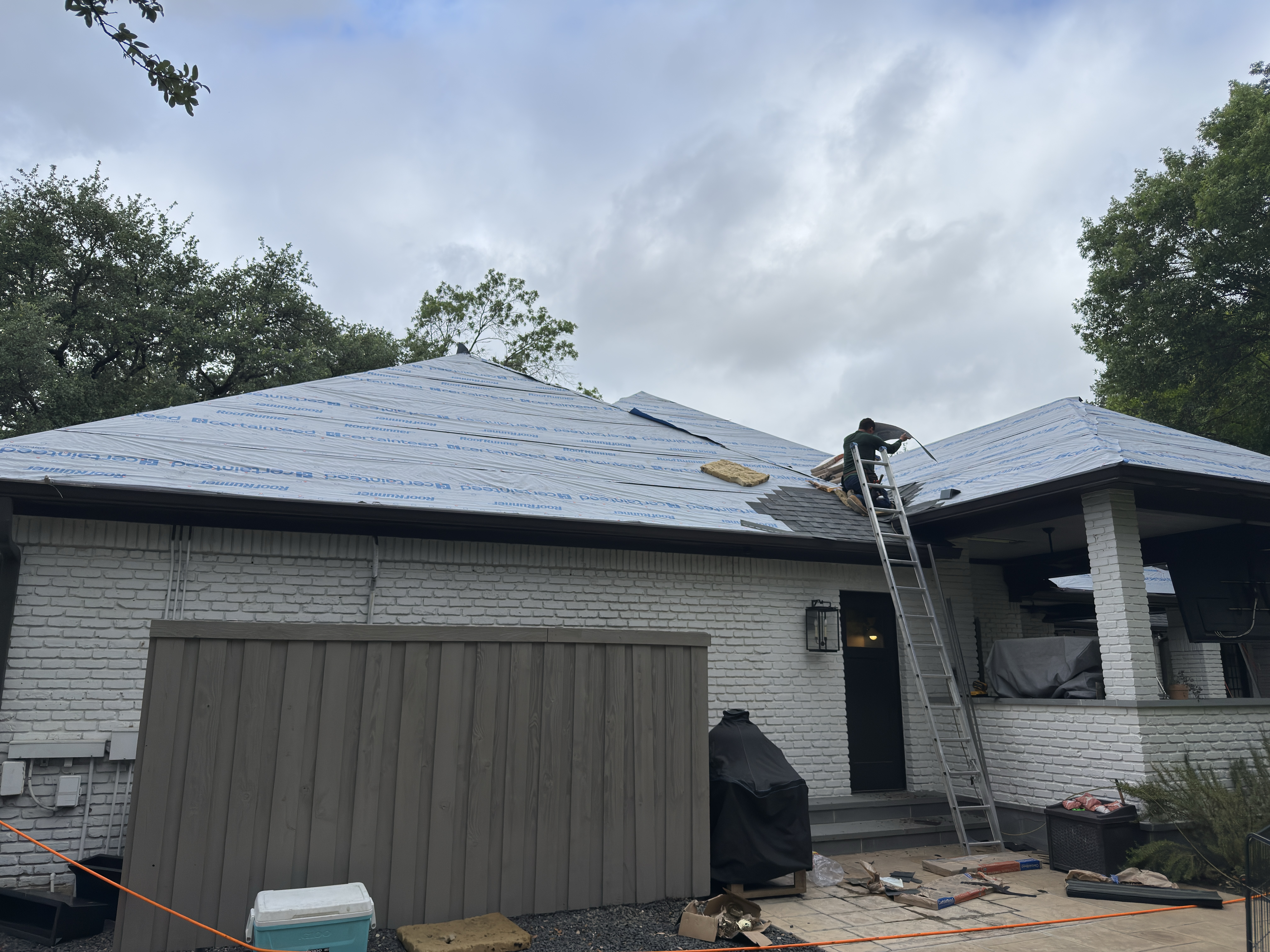 Roof Pros Dallas crew member on a ladder installing roofing materials