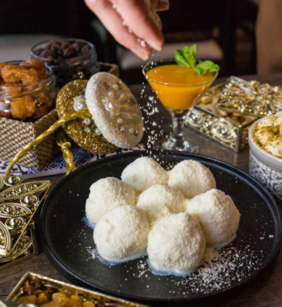 Premium Bengali mithai — hand-dusted rasgulla on black plate