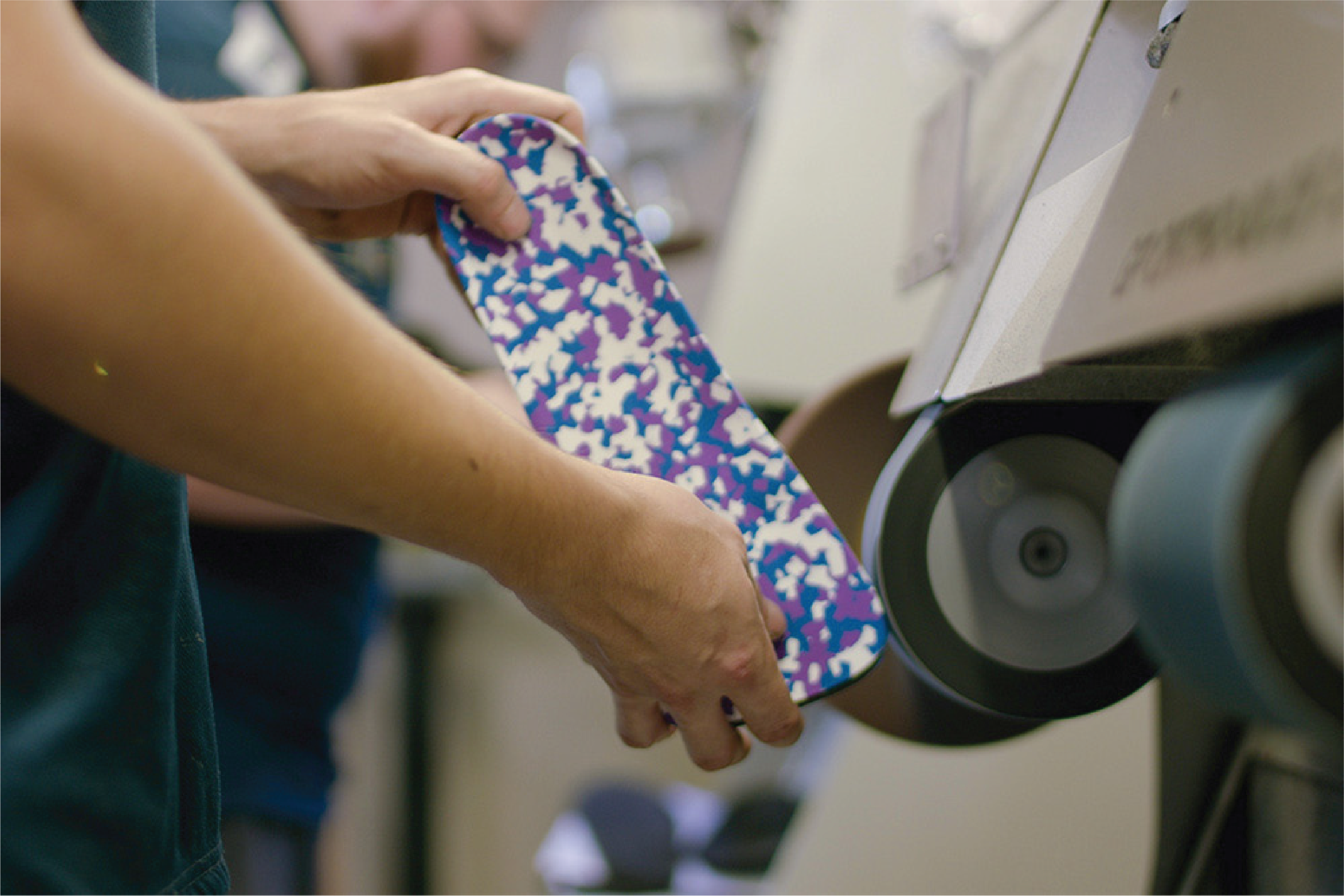 A clinician shapes a custom orthotic on a sanding wheel
