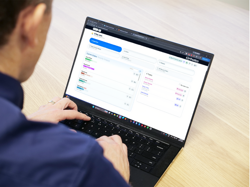 A clinician using the iOrthotics iOrder dashboard on a laptop