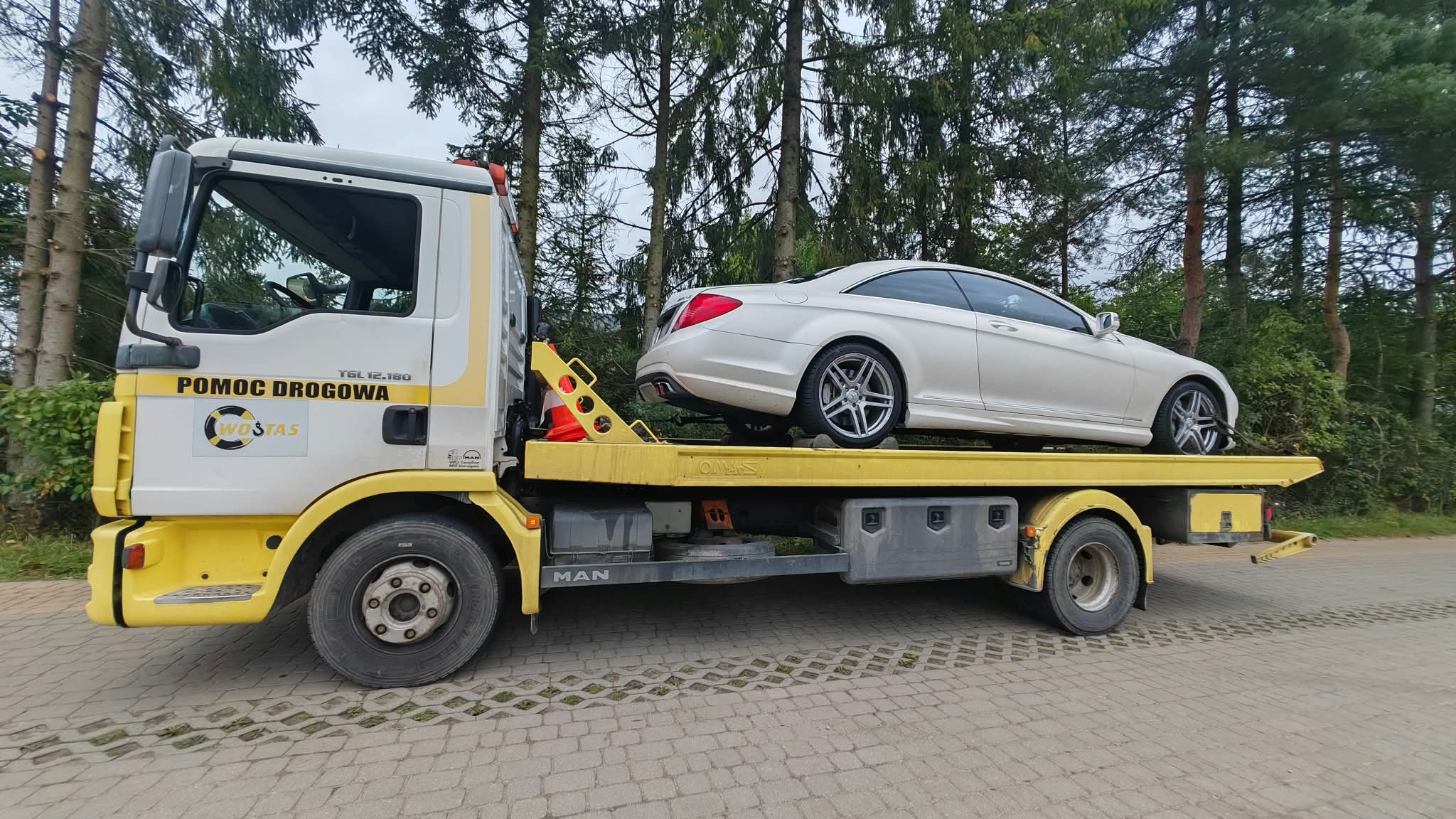 Laweta Słupsk – biały Mercedes kabriolet na platformie przy lesie