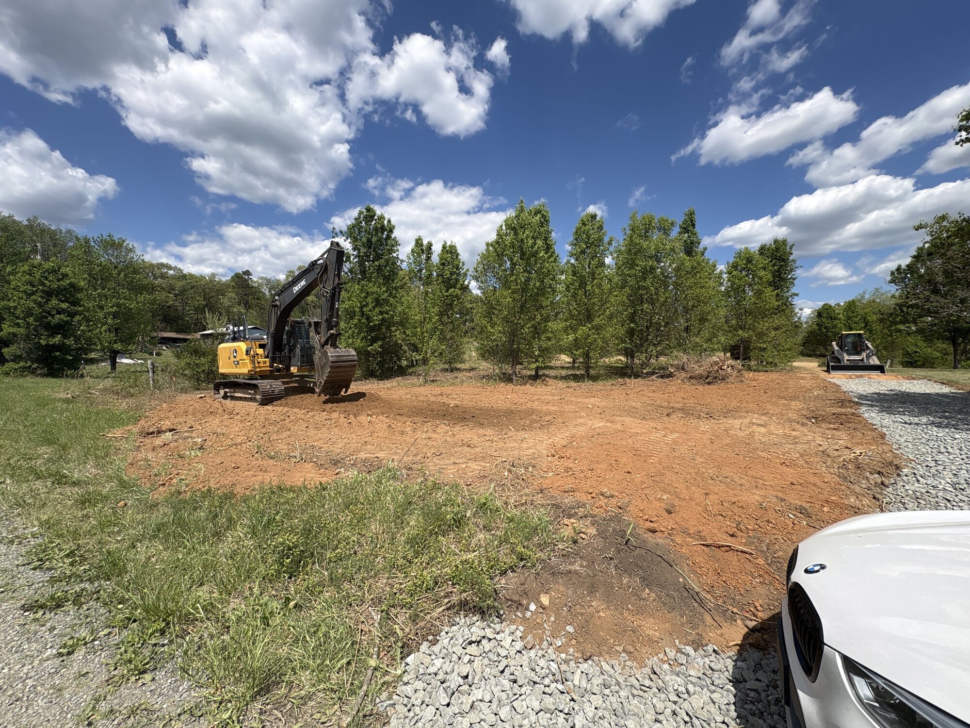 Bailey Builds excavator grading a cleared building pad of red Virginia clay