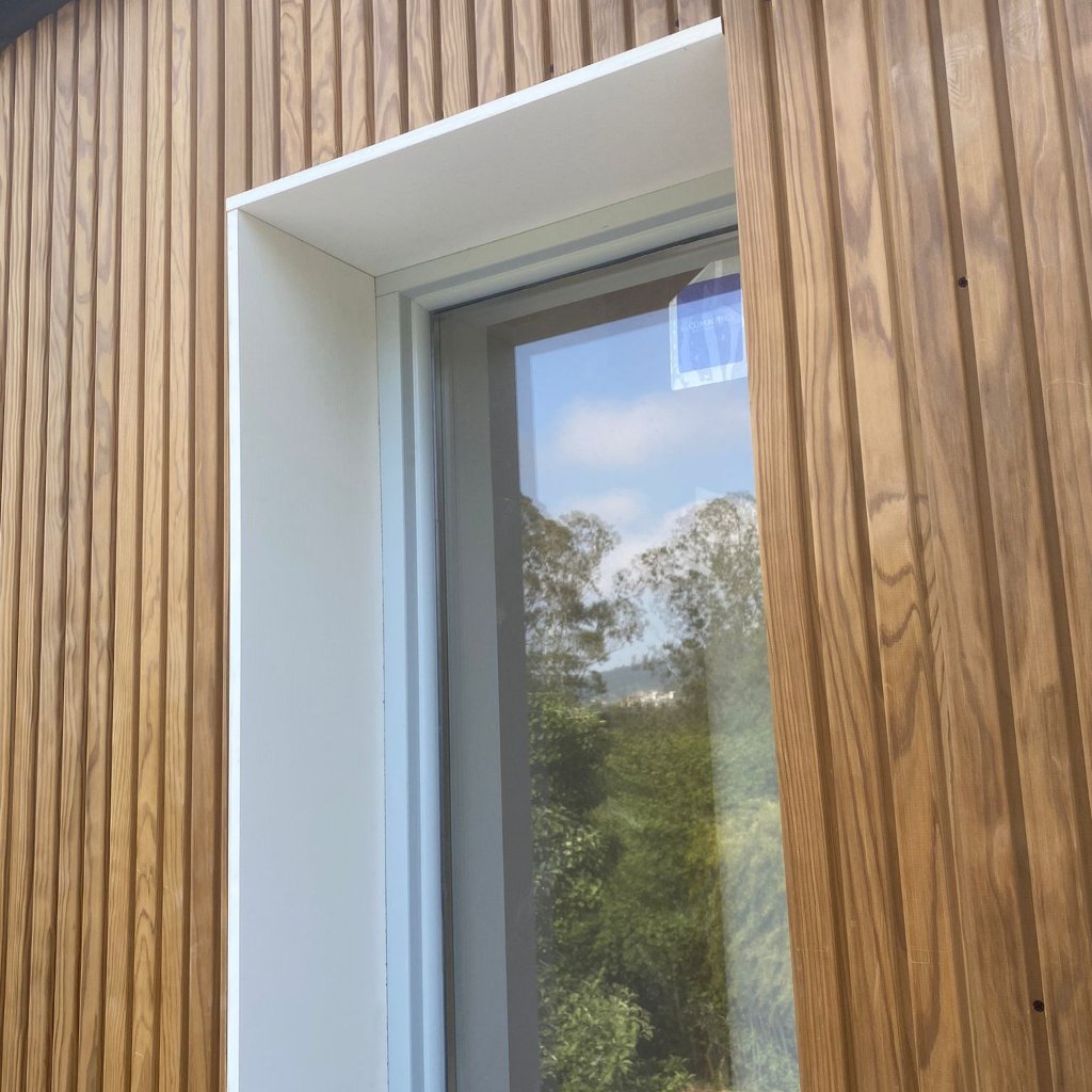Ventana de PVC con marco blanco instalada en fachada de madera