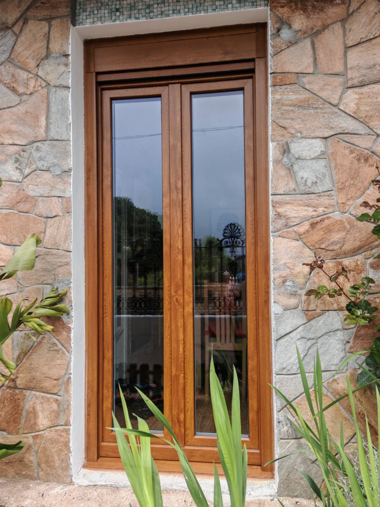 Ventana acabado madera en muro de piedra