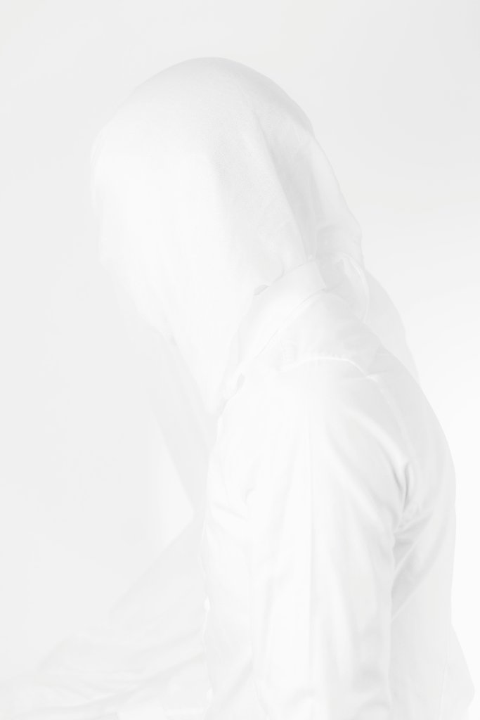A hooded figure dissolving into a white background — invisible