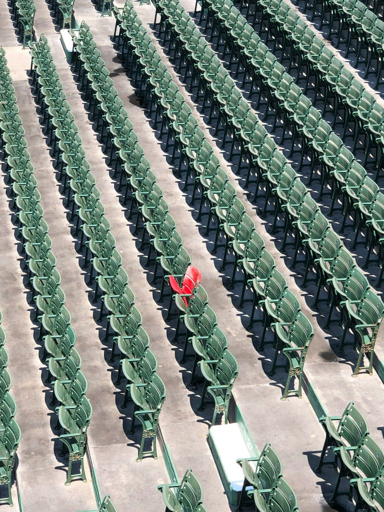 A stadium of identical green seats with one red seat — unremarkable