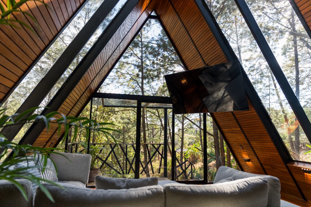 Interior de cabaña A-frame con vista al bosque de pinos