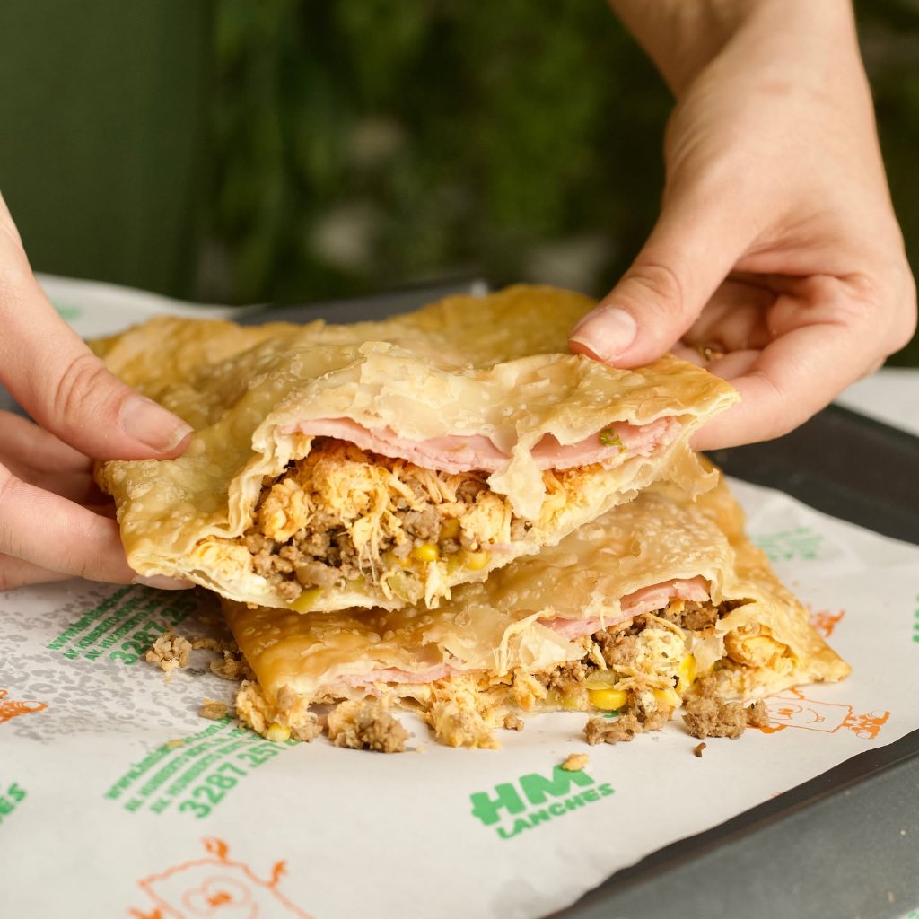 Pastel gigante dourado partido ao meio com recheio de carne, frango e milho