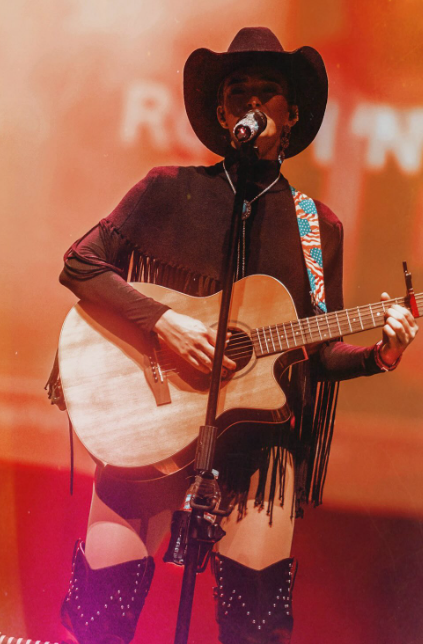 Camryn Marie singing with guitar in warm stage light