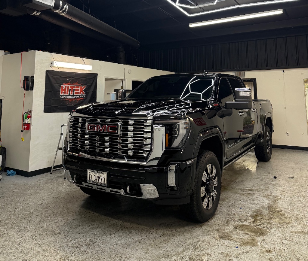 Black GMC Denali HD pickup truck with tinted windows inside the detailing bay