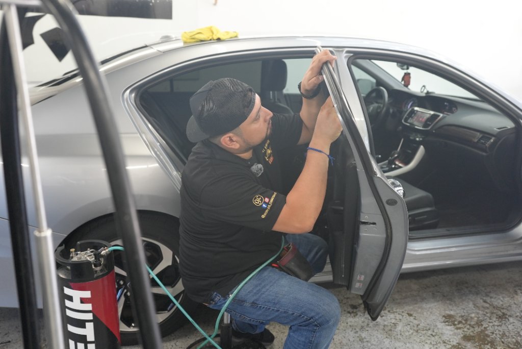 Royal Window Tint technician applying film to a sedan inside the shop