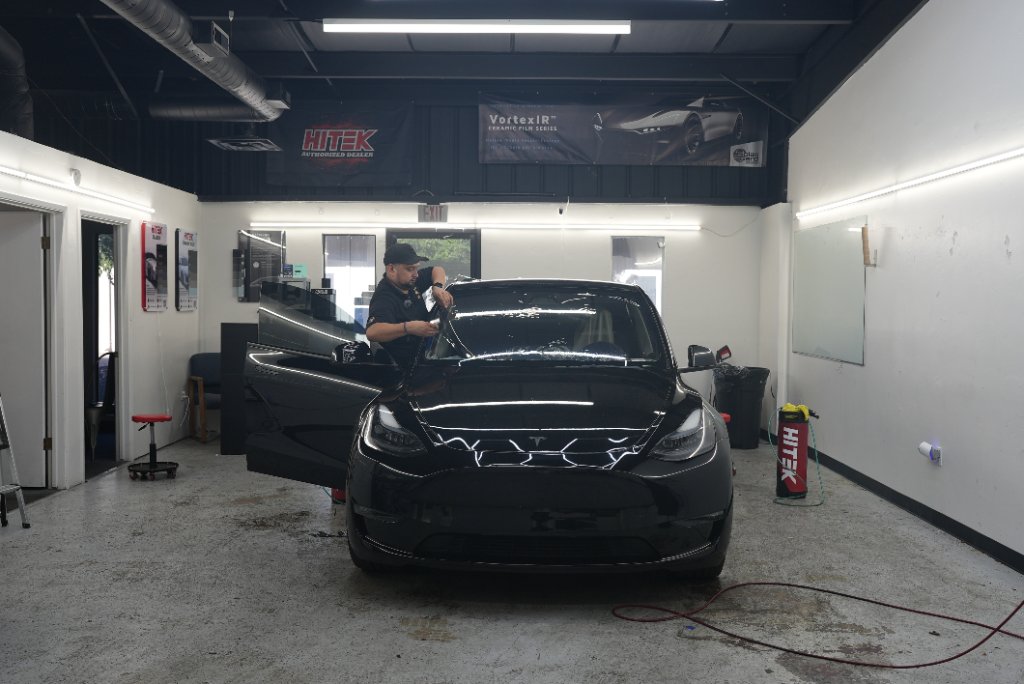 Technician working on a black Tesla inside the Royal Window Tint shop in Turlock