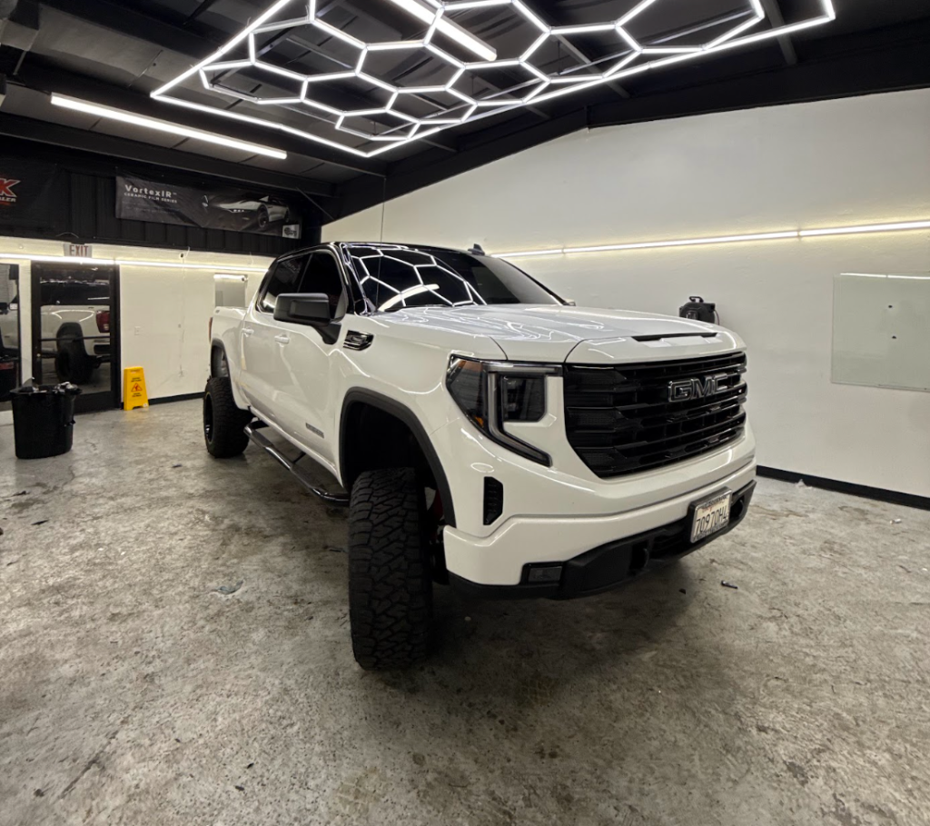 Lifted white GMC Sierra inside the Royal Window Tint shop