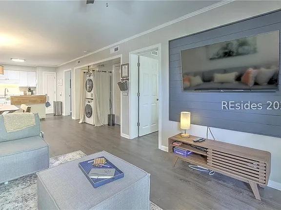 Open-concept living area of the Big Sur villa with a slate shiplap accent wall, wall-mounted TV, and light wood flooring