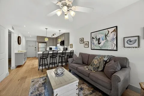 Living room of 239 Beach City Road Apt 2310 with gray sofa, coastal art, and open view to the kitchen
