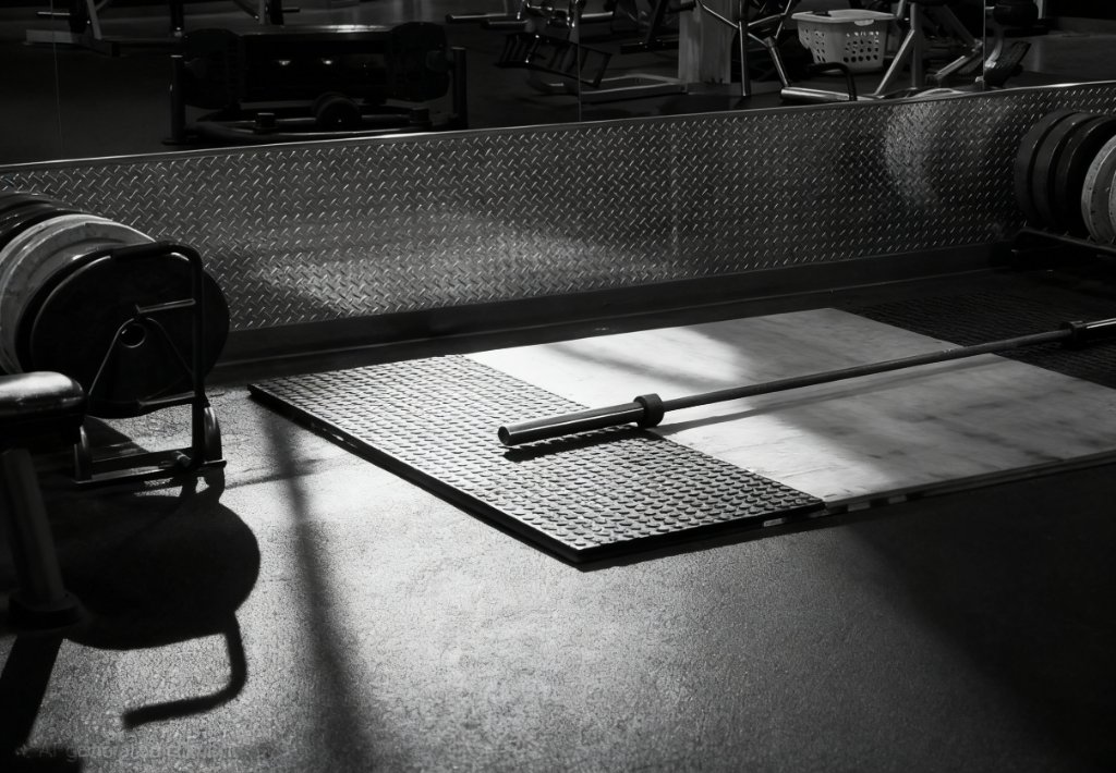 Weightlifting platform with barbell and mirrored wall