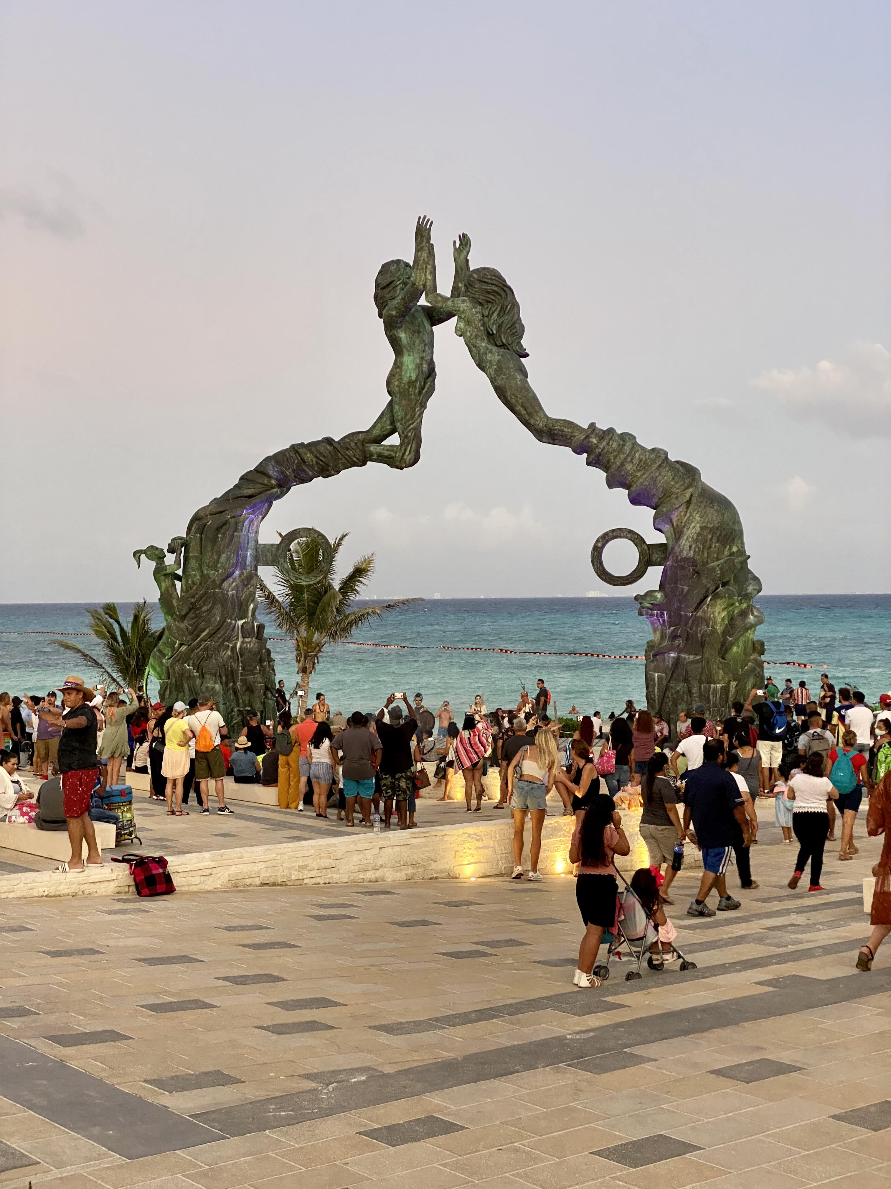 The Portal Maya sculpture on the Playa del Carmen waterfront, two bronze figures forming an arch overlooking the Caribbean Sea